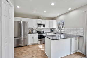 Kitchen featuring appliances with stainless steel finishes, white cabinets, tasteful backsplash, and recessed lighting