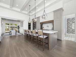 Kitchen with a large island, wood finished floors, light countertops, gray cabinetry, and beamed ceiling