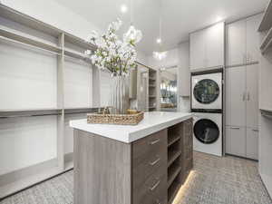 Walk in closet featuring stacked washer / dryer and light carpet