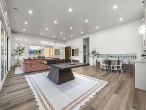 Kitchen with open floor plan, a center island, light wood-type flooring, dark countertops, and recessed lighting