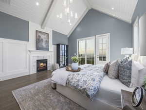 Bedroom featuring wood finished floors, a tile fireplace, a chandelier, wooden ceiling with exposed beams, and high vaulted ceiling