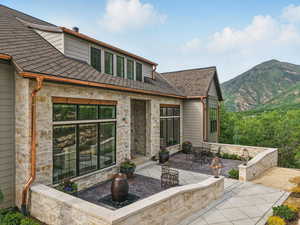 Back of property with a patio area, stone siding, and a mountain view
