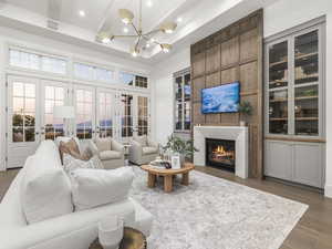 Living area featuring french doors, wood finished floors, a glass covered fireplace, a chandelier, and recessed lighting