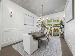 Dining room with a decorative wall, wood finished floors, and a chandelier