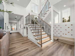 Staircase with wood finished floors, a high ceiling, recessed lighting, and baseboards
