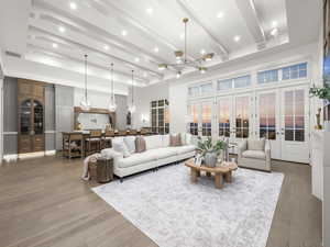 Living area featuring french doors, light wood-style flooring, a chandelier, a high ceiling, and recessed lighting