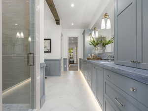 Bathroom with double vanity, a shower stall, a wainscoted wall, recessed lighting, and beam ceiling