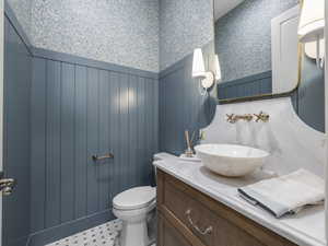 Bathroom featuring wallpapered walls, a wainscoted wall, vanity, and toilet
