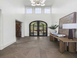 Entryway featuring french doors, a chandelier, a towering ceiling, arched walkways, and healthy amount of natural light