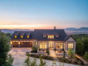 View of front of home with driveway, a mountain view, a chimney, a garage, and a shingled roof