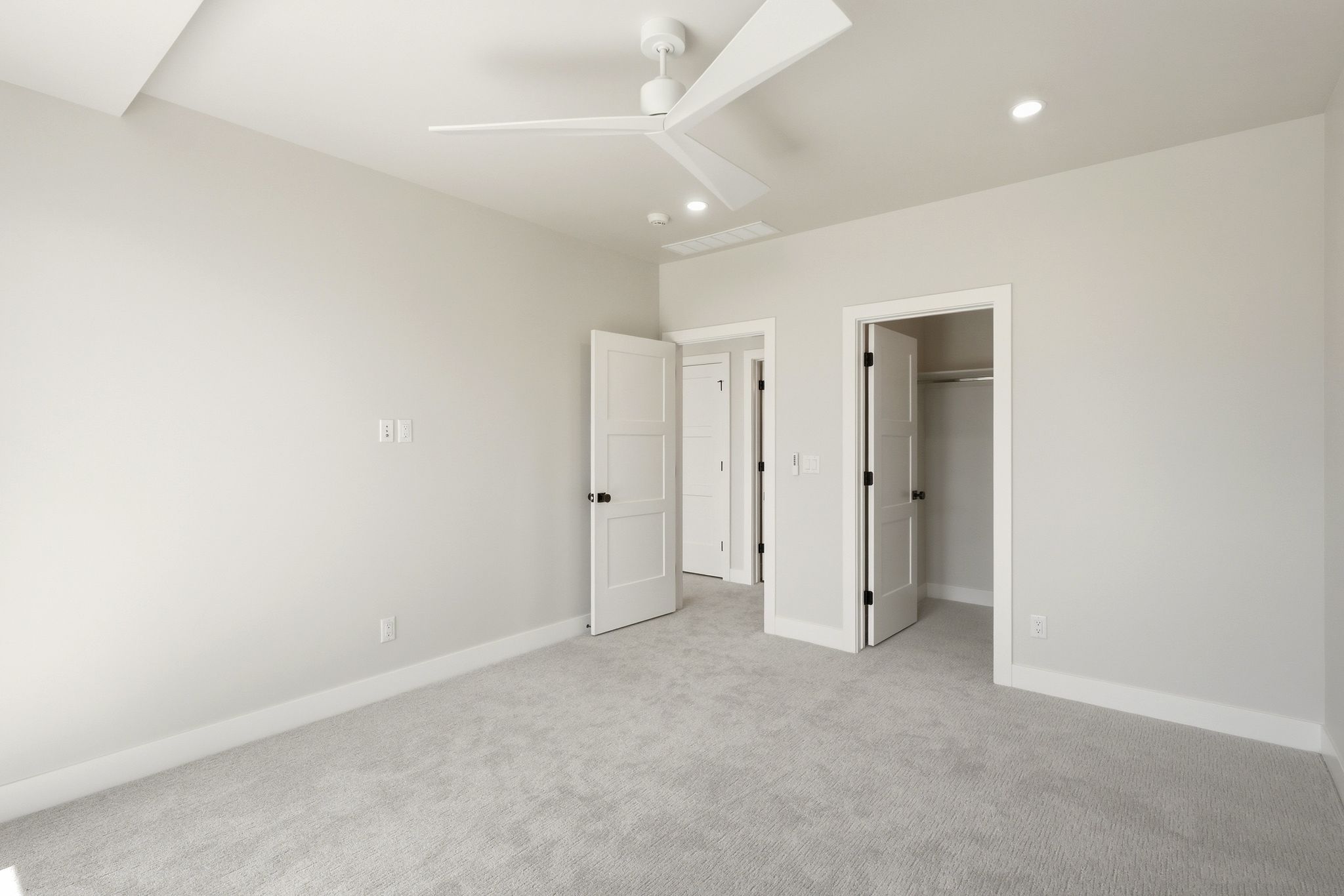 Neutral-toned bedroom featuring light grey carpeting and crisp white trim