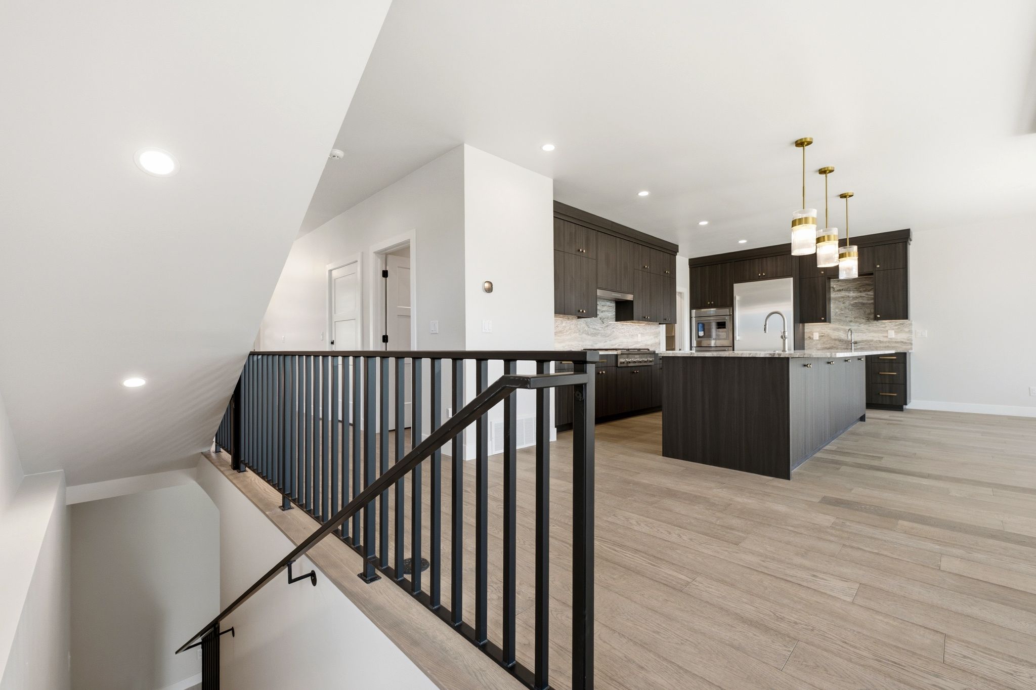Modern kitchen featuring dark wood-finish cabinetry, a large island with sink, and stainless steel appliances