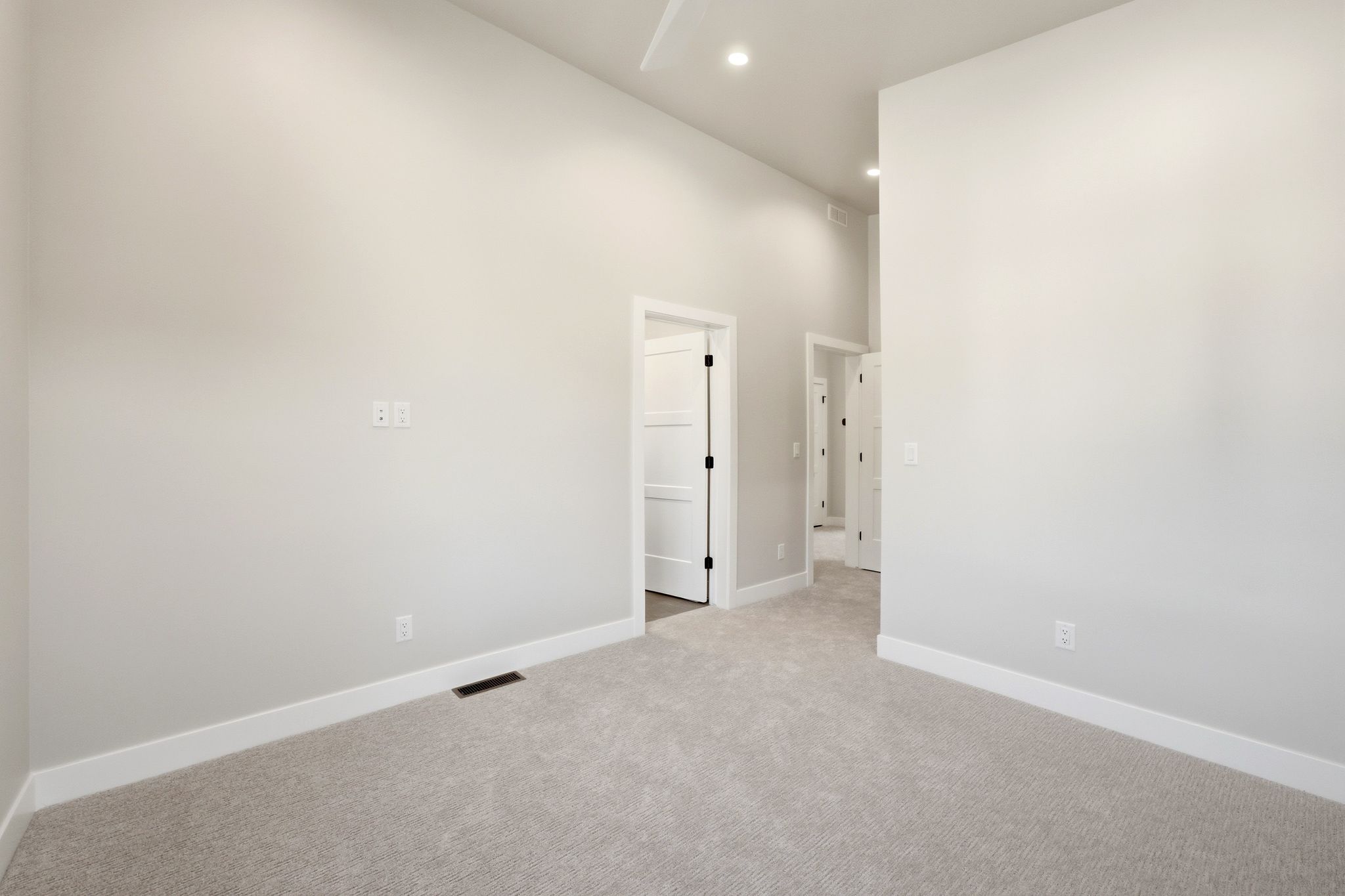 Spacious room featuring vaulted ceilings, light gray wall paint, and plush gray carpeting