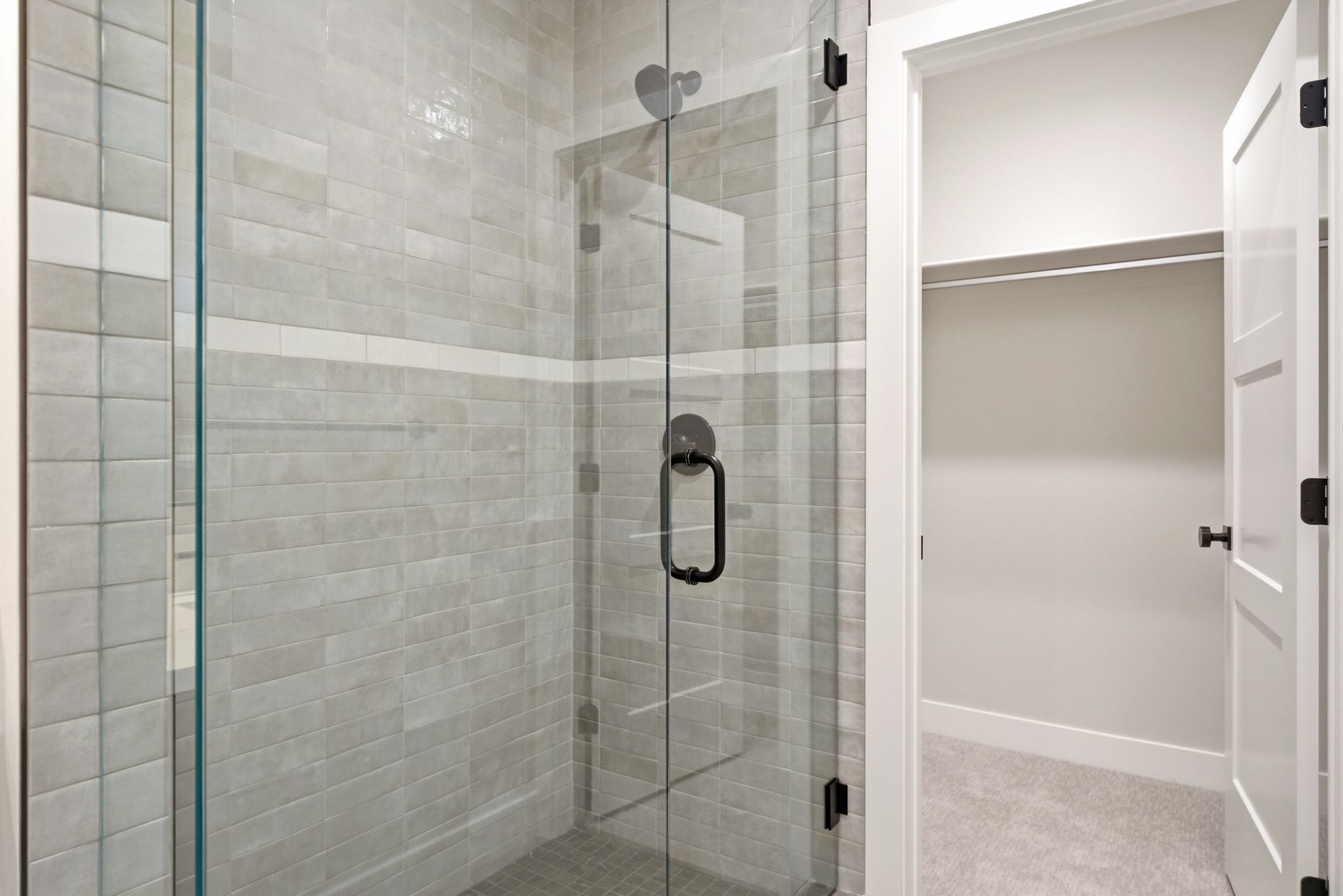 Walk-in shower with clear glass enclosure and matte black hardware