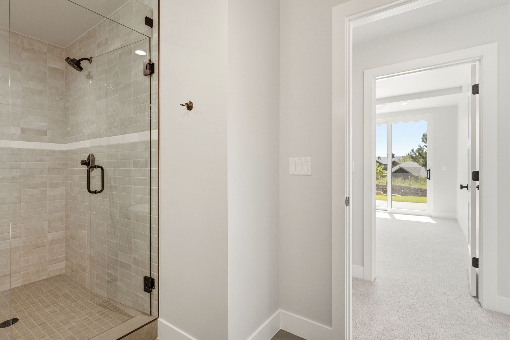 Walk-in shower featuring glass enclosure, subway tile surround with accent band, and dark bronze fixtures