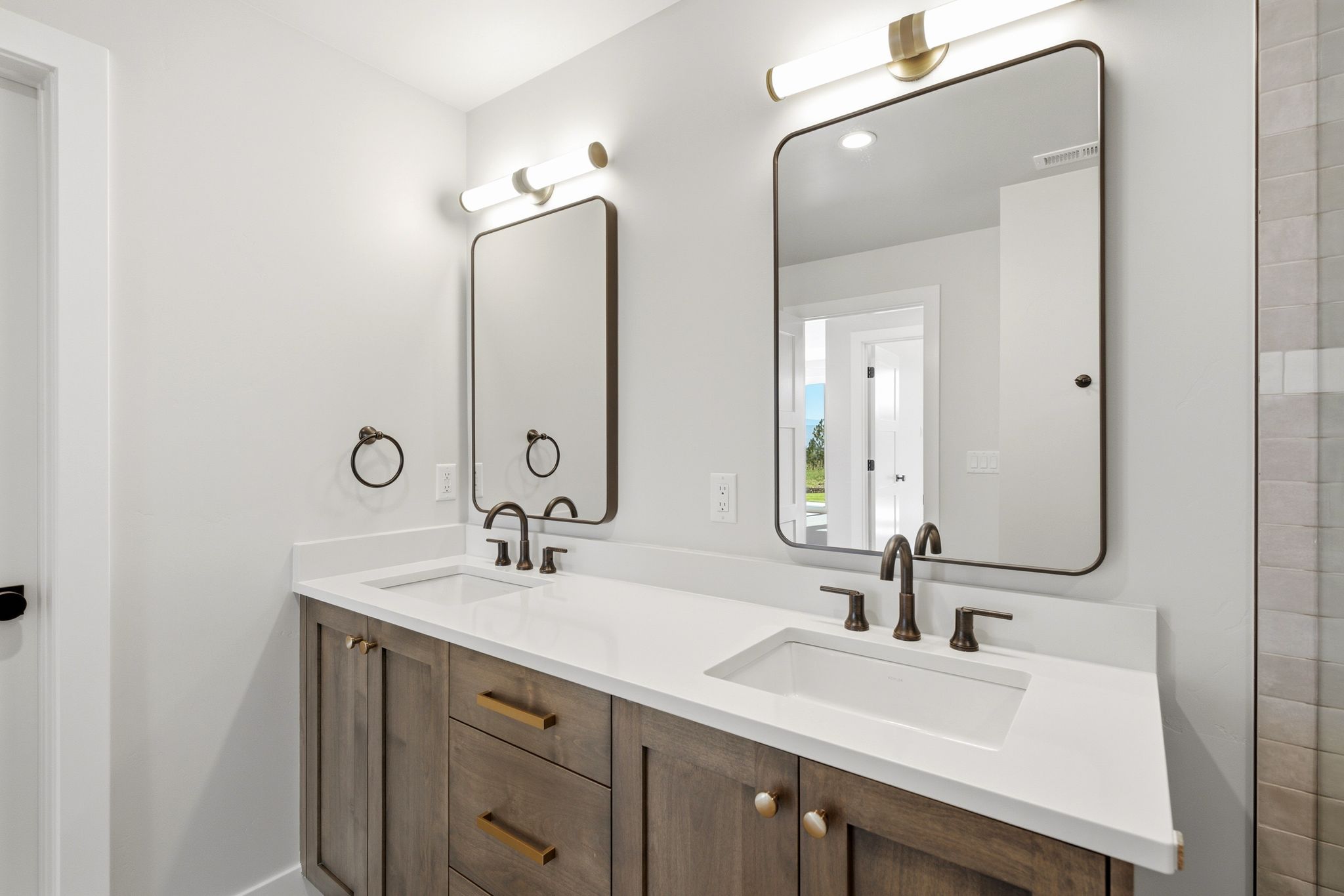 Dual vanity with wood-finish cabinetry, white countertops, and integrated rectangular sinks