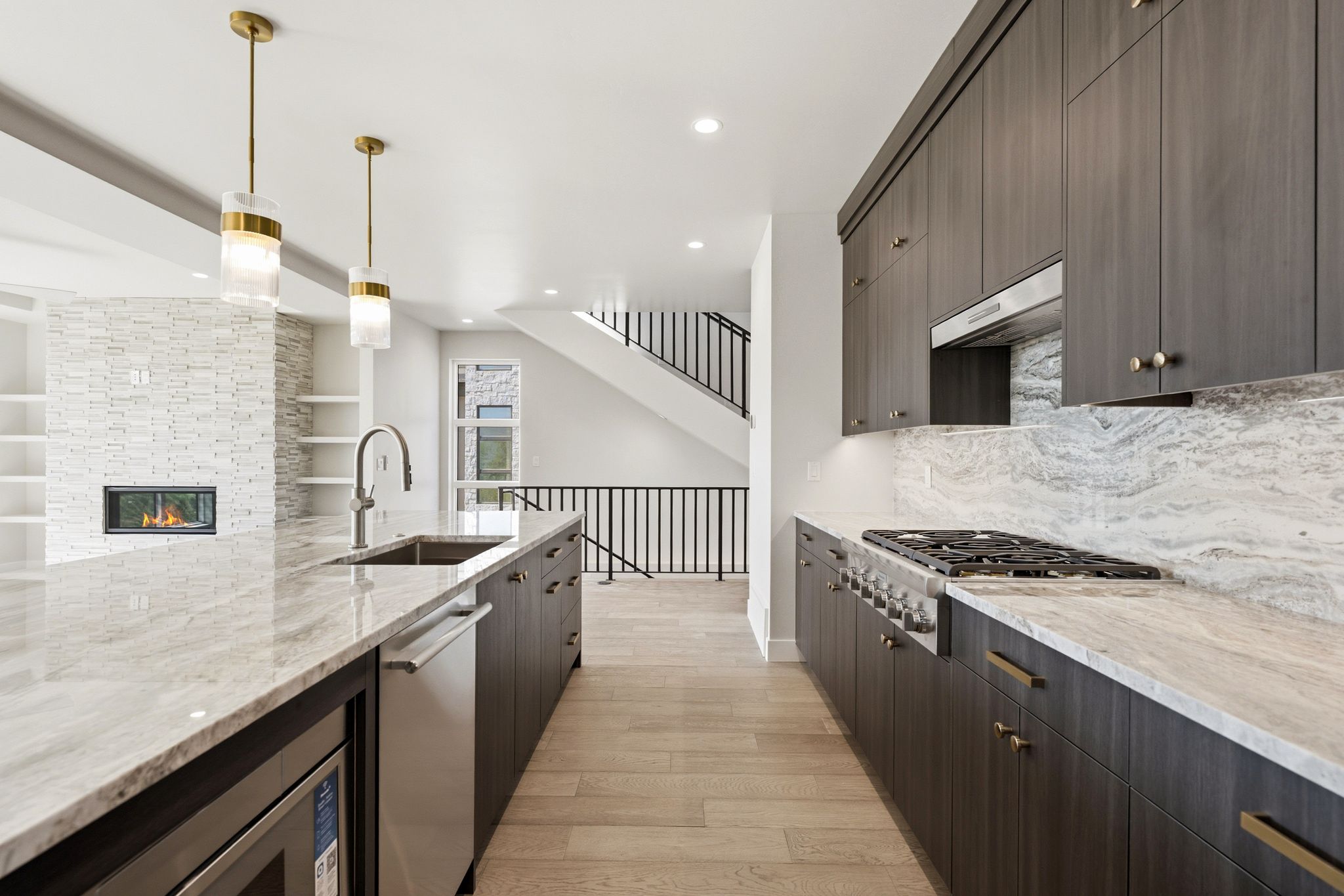 Modern kitchen featuring wood-finish cabinetry, light stone countertops, stainless steel appliances, and a gas range