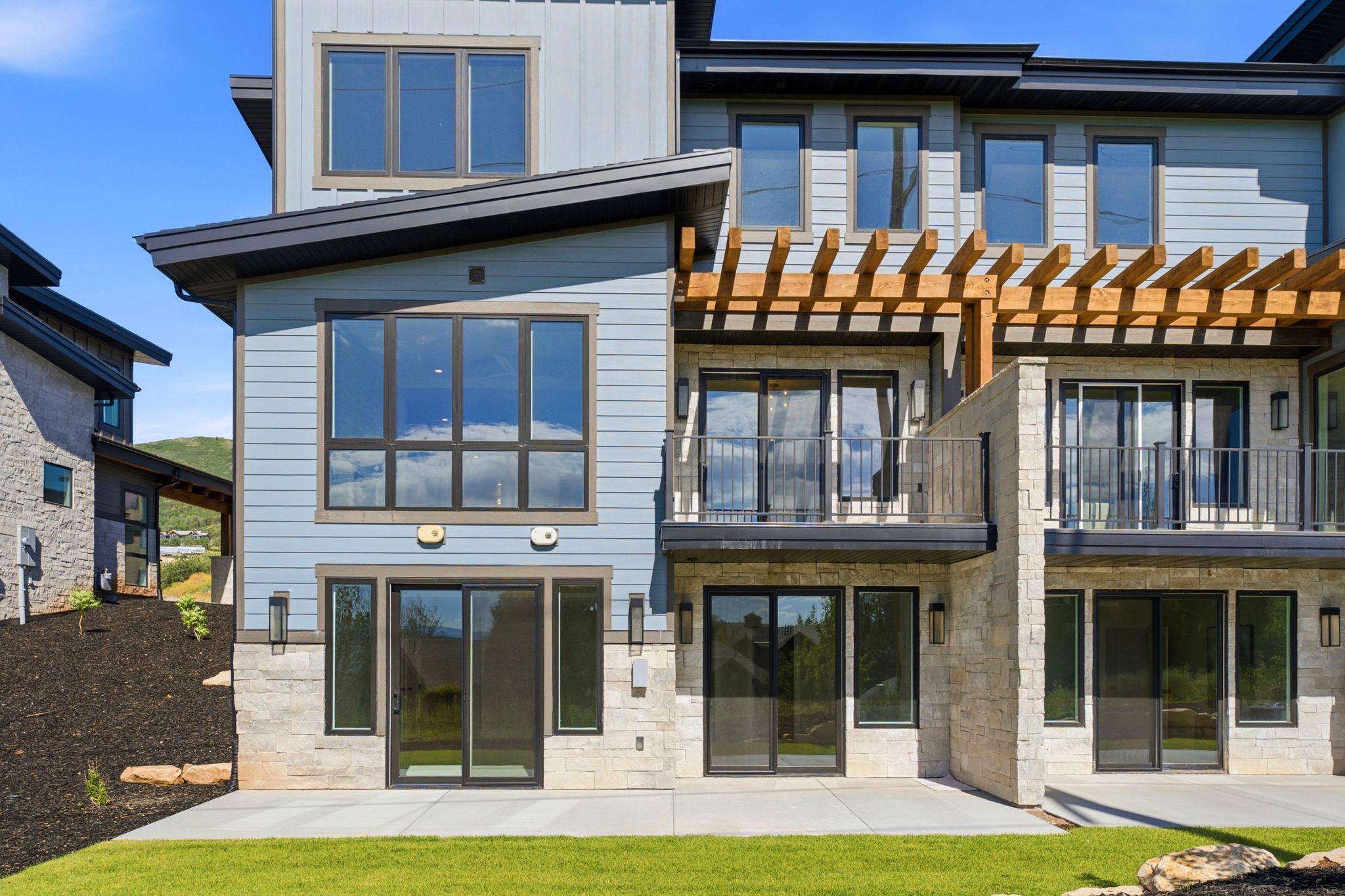 Modern multi-level exterior featuring light blue siding and stone veneer accents