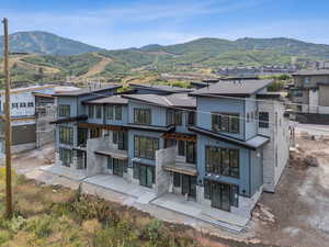 Back of property with stone siding, a mountain view, board and batten siding, and a residential view