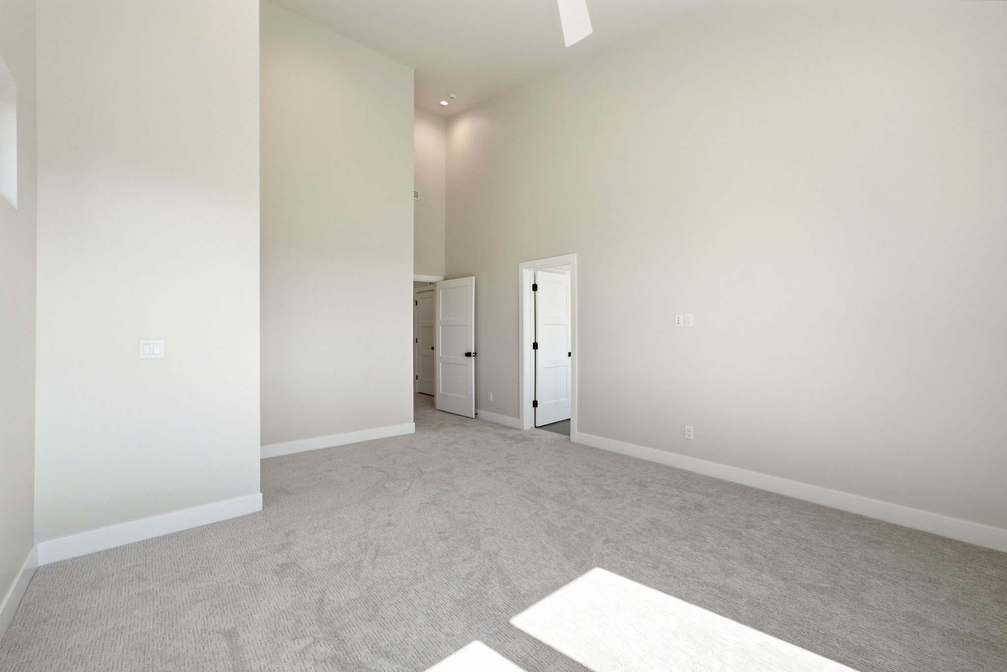 Spacious room featuring vaulted ceilings, light gray carpeting, and white trim