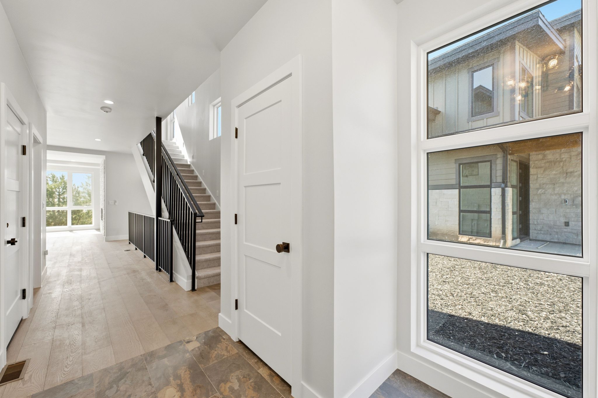 Entryway featuring light wood-finish flooring, a contemporary black metal staircase railing, and white walls
