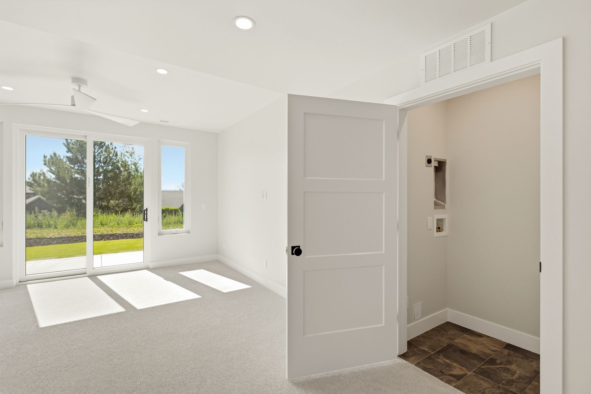 Bright room featuring light gray carpeting, recessed lighting, and a modern ceiling fan