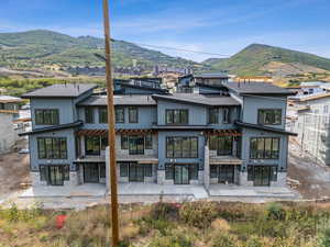 Rear view of house with stone siding, a mountain view, and a patio area