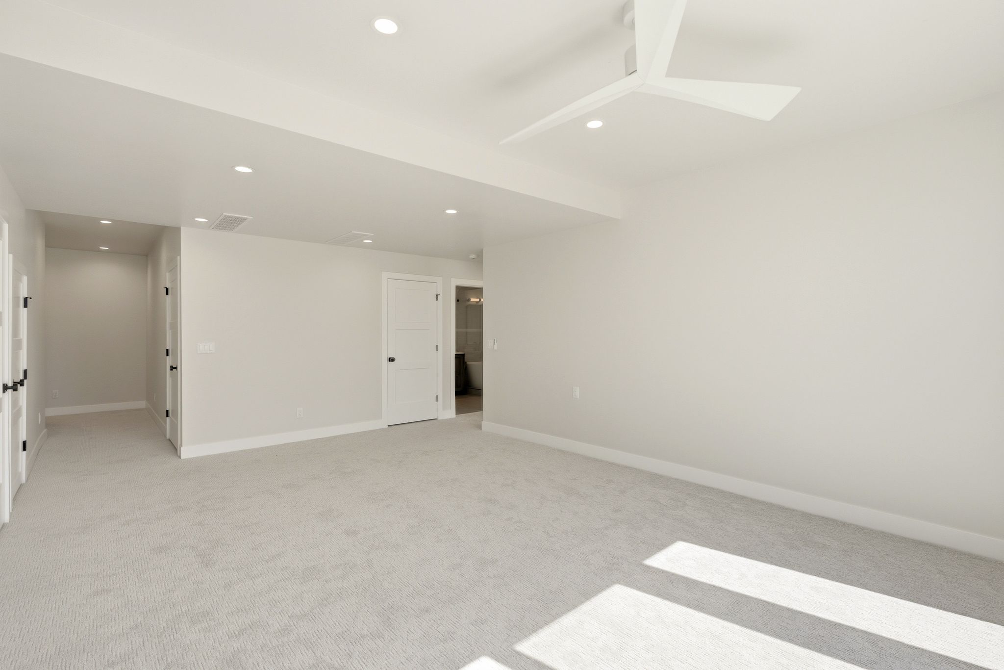 Spacious interior featuring neutral carpeting, recessed lighting, a modern ceiling fan, and white trim throughout