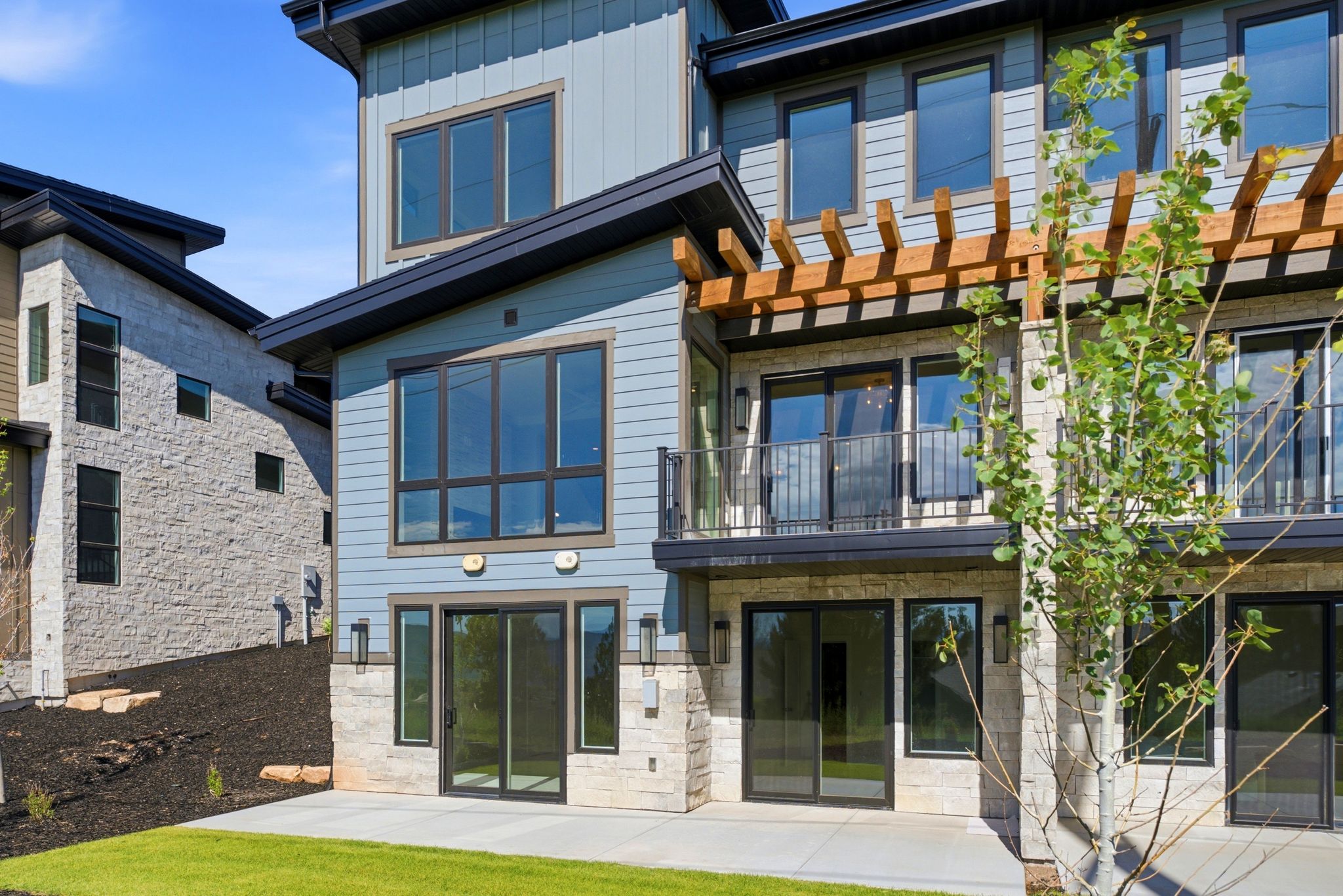 Modern multifamily architecture featuring varied siding, stone veneer accents, and a ground-level patio