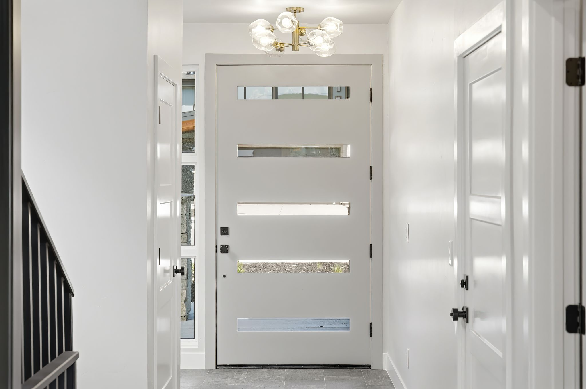 Entryway featuring a modern door with multiple horizontal lites, a contemporary ceiling light fixture, a sidelite, and grey floor tiles