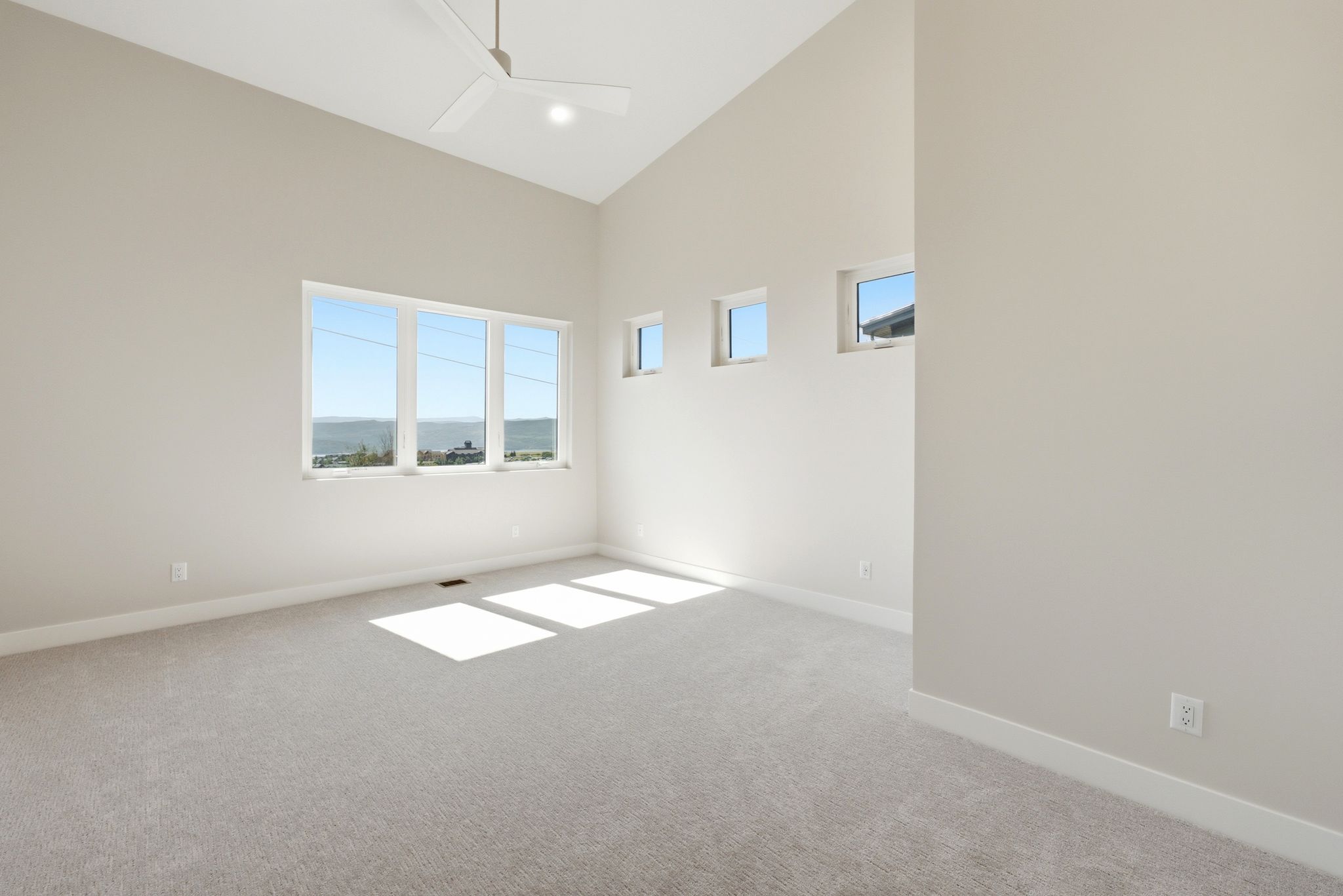 Spacious interior room featuring a vaulted ceiling and light-toned carpeting