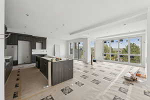 Kitchen featuring a center island, dark brown cabinetry, a raised ceiling, and open floor plan
