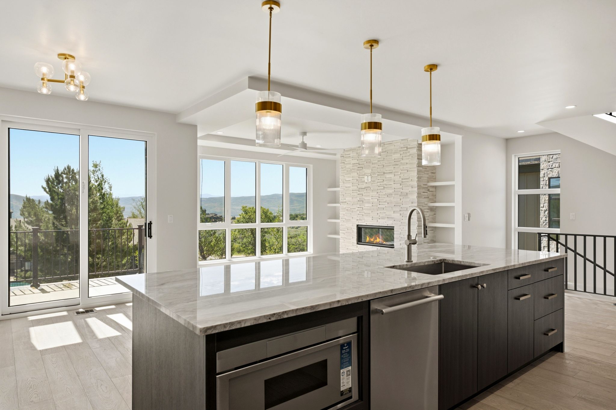 Modern kitchen island featuring a light-toned countertop, integrated stainless steel appliances, and dark wood-finish cabinetry