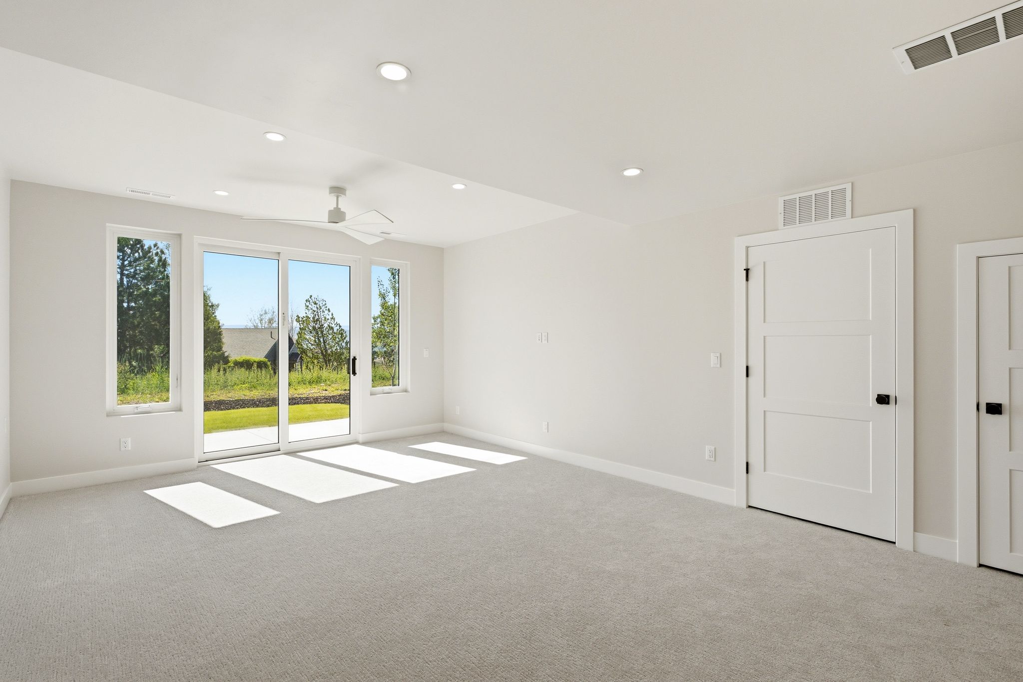 Spacious room featuring light-colored carpeting, recessed lighting, and a contemporary ceiling fan