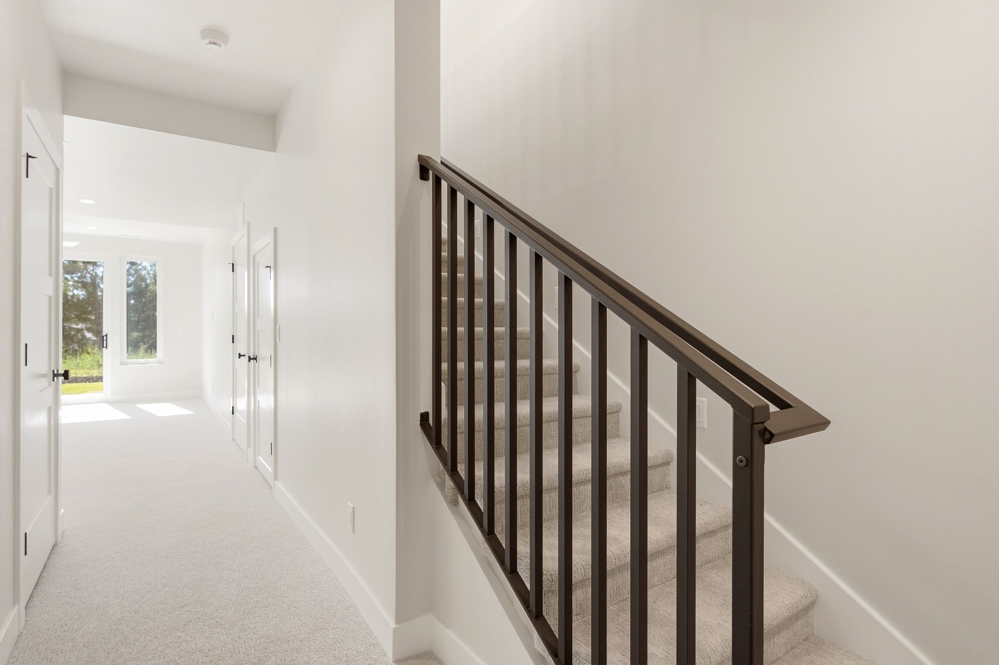 Staircase with contemporary dark-toned metal balusters, carpeted treads, and a clean white wall finish