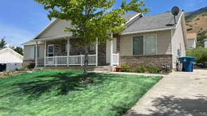 View of front of house featuring brick siding, covered porch, and a front lawn