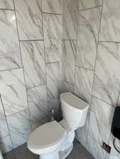 Bathroom featuring toilet and tile walls