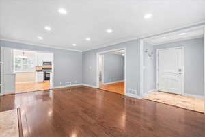 Unfurnished living room with ornamental molding, wood finished floors, recessed lighting, and baseboards