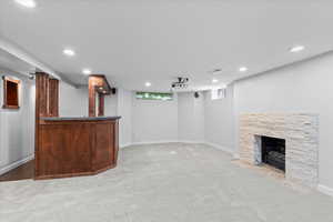 Indoor dry bar featuring carpet floors, a stone fireplace, recessed lighting, and baseboards