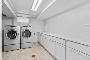 Washroom with washer and clothes dryer and cabinet space and utility sink