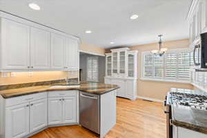 Kitchen featuring appliances with stainless steel finishes, white cabinets, light wood-style floors, a sink, and a chandelier