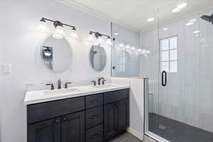 Full bathroom with double vanity, a stall shower, ornamental molding, and tile patterned flooring