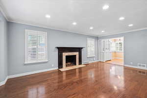 Unfurnished living room with crown molding, wood finished floors, recessed lighting, a fireplace, and baseboards