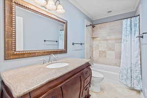 Bathroom with vanity, toilet, ornamental molding, shower / bathtub combination with curtain, and tile patterned flooring