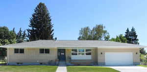 Single story home with a front lawn, a garage, brick siding, and concrete driveway