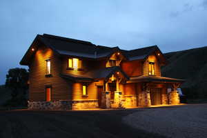 View of front of house featuring a standing seam roof, a garage, stone siding, metal roof, and driveway