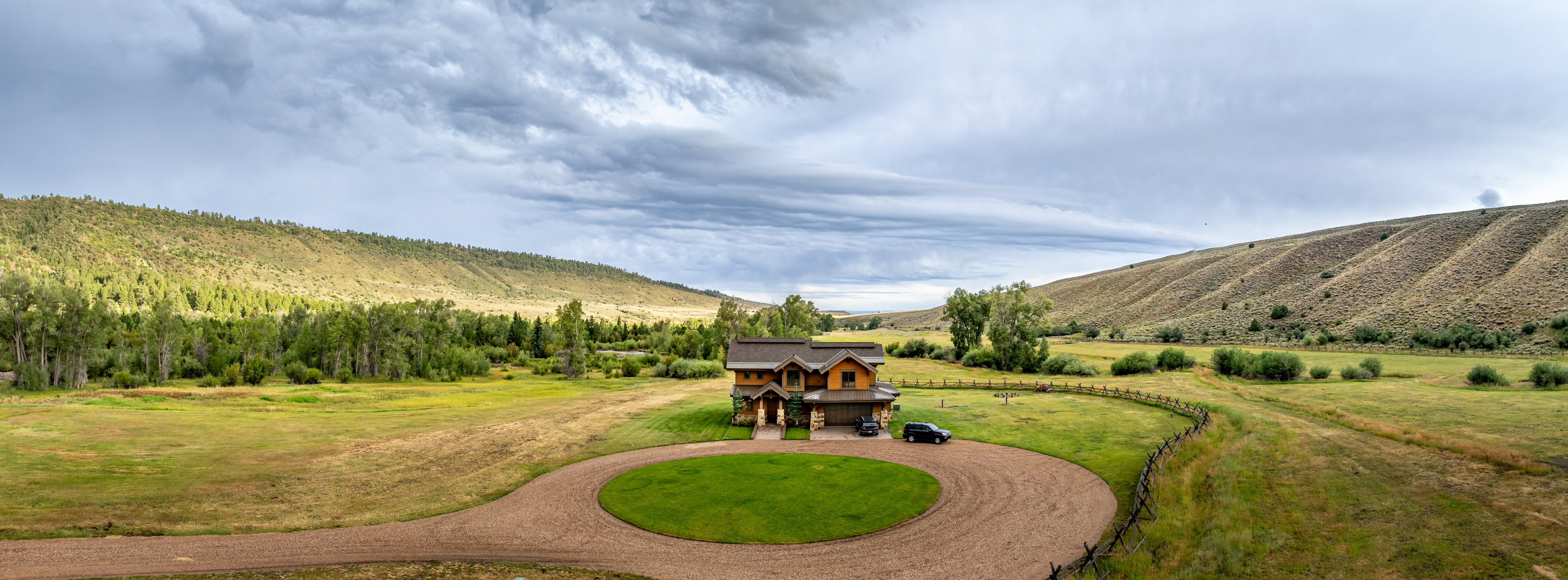 View of grassy yard featuring curved driveway, a rural view, and a mountain view