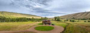 View of grassy yard featuring curved driveway, a rural view, and a mountain view