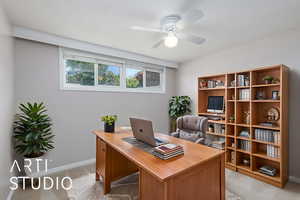 Office area with a ceiling fan, baseboards, and light colored carpet