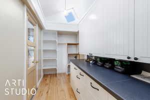 Walk in closet with light wood finished floors and vaulted ceiling